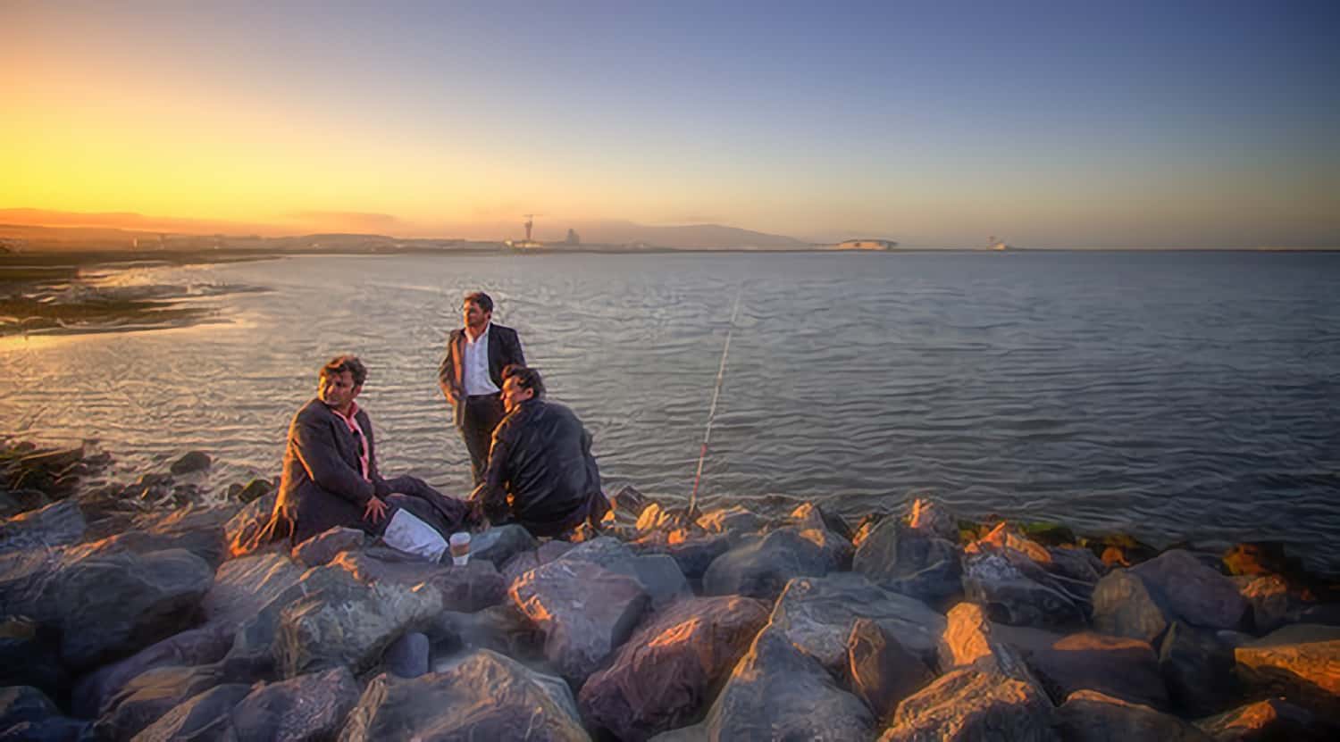 Three men fishing in fine shoes and sport coats. Source.